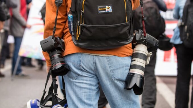 Magazine actualités par des professionnels : Une source fiable d’information et d’analyse journaliste professionnel en jean bleu et sac à dos orange marchant dans la rue pendant la journée