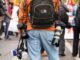journaliste professionnel en jean bleu et sac à dos orange marchant dans la rue pendant la journée