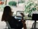 femme assise sur une chaise devant une table avec un ordinateur portable pour mettre en place une stratégie digitale pour son commerce