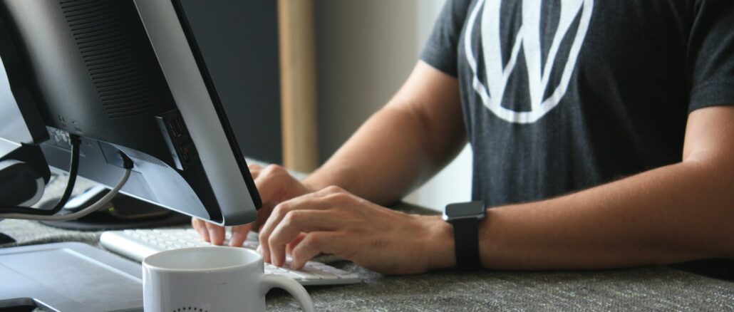 Webmaster Wordpress en t-shirt noir et blanc utilisant un ordinateur