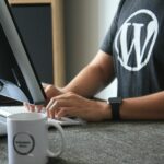 Webmaster Wordpress en t-shirt noir et blanc utilisant un ordinateur