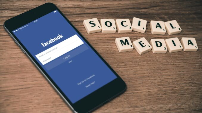 Informations et médias sociaux iPhone 6 gris sidéral avec écran de connexion Facebook à proximité des tuiles de Scrabble des réseaux sociaux