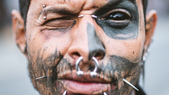 homme avec un piercing au nez argenté et d'autres sur son visage